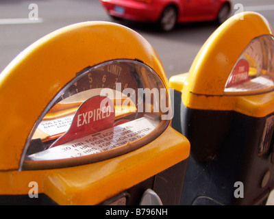 Expiré parcmètre avec voiture rouge qui passent sur road dans le centre de Corvallis, Oregon. Banque D'Images