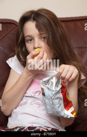A young girl eating chips / frites - junk food snack Banque D'Images