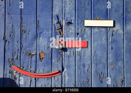 Une porte peinte en bleu et rouge peeling au cadenas sur Hasp un atelier de Ramsgate Harbour Banque D'Images