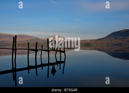 Femme debout sur la jetée, Brandelhow Derwent Water, Parc National de Lake District, Cumbria, Angleterre, Royaume-Uni Banque D'Images