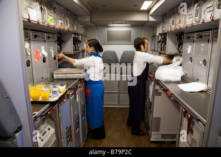 Deux membres de l'équipage de cabine travaillant / ranger dans la cuisine sur Gulf Air Airbus A330 en vol à Bahreïn de Londres Banque D'Images