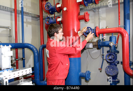 Un employé de l'Schmack Biogas AG réglementant la distribution de chauffage avec un appareil de commande de la pompe dans le bâtiment technique Banque D'Images