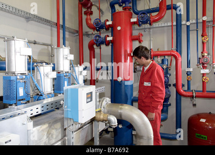 Un employé de l'Schmack Biogas AG réglementant la distribution de chauffage avec un appareil de commande de la pompe dans le bâtiment technique Banque D'Images