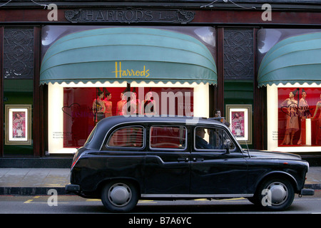 Taxi en face d'une vitrine de magasin Harrods, Londres, Angleterre, Grande-Bretagne, Europe Banque D'Images