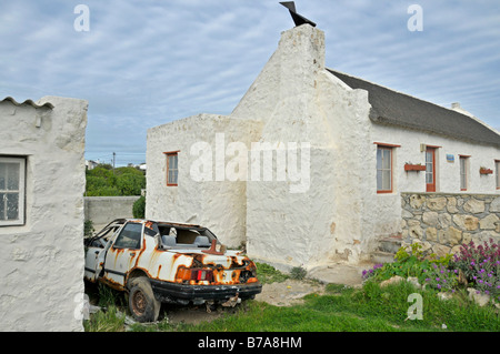 Carcasse de voiture rouillée et maisons de familles de pêcheurs dans Kassiesbaai noir près de Arniston, West Kap, Afrique du Sud Banque D'Images