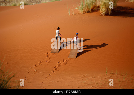 Une vue panoramique de deux filles grimper au sommet d'une dune alors que des sables sur les dunes de Sossusvlei Banque D'Images