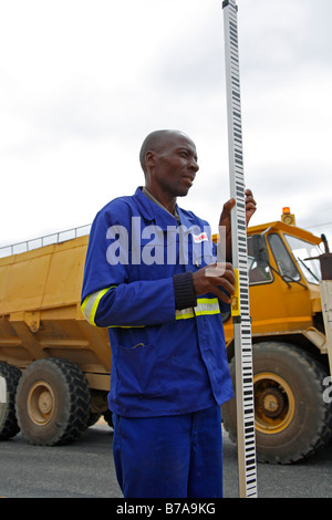 Un assistant de géomètres tenant un bâton au cours de la construction de routes travaux d'enquête Banque D'Images