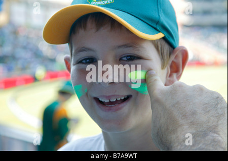 Smiling boy soutenant le Cricket sud-africain ayant côté son visage peint dans les couleurs de l'Afrique du Sud (Modèle 1992) Banque D'Images