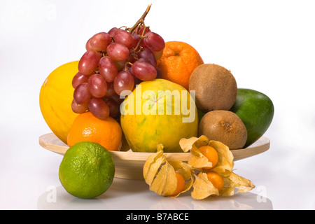 Les fruits exotiques sur une plaque de bois, melon, raisin, orange, citron vert, physalis, kiwis, mangue, papaye Banque D'Images