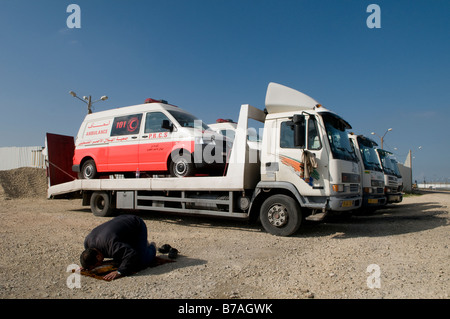 Un musulman prie à côté d'ambulances prêts à entrer dans la bande de Gaza à la frontière de Kerem Shalom dans le sud d'Israël Banque D'Images