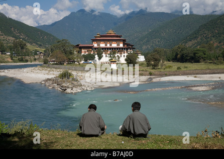 Deux hommes habillés en bhoutanais ghos traditionnels donnent sur Punaka Dzong du Bhoutan Banque D'Images