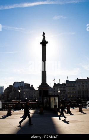 La colonne Nelson, silhouetté par le soleil à Trafalgar square avec des piétons en train de marcher par le Nov 16 2007 à Londres Banque D'Images