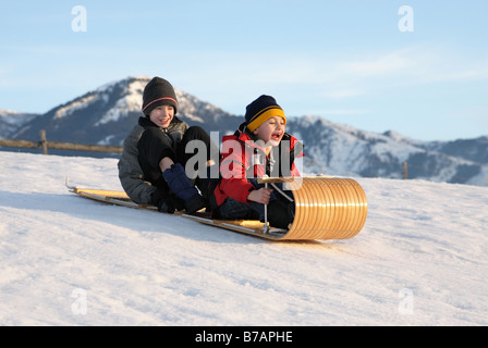 Deux garçons dans une descente en luge sur une piste de luge avec expressions excité Banque D'Images