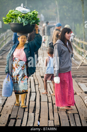 Mon femme transportant des légumes sur sa tête en bois traversant le pont en teck à Sangklaburi en Thaïlande Banque D'Images