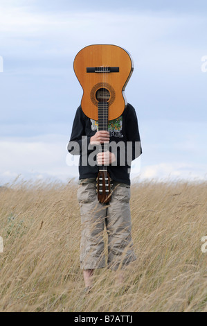 Boy Holding Guitar in Field Banque D'Images