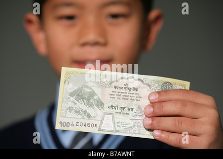 "L'école Népalaise garçons tenant une cent rupee note" Banque D'Images