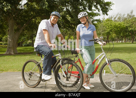 Couple Riding Bikes dans le parc Banque D'Images