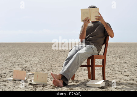 L'homme la lecture de livres sur la plage Banque D'Images