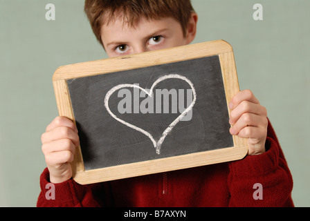 Boy Holding Tableau avec coeur dessiné dessus Banque D'Images