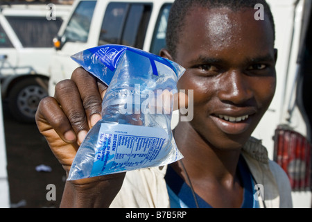 Jeune homme vendant de l'eau potable à la station de bus ou à la Gare Routière Pompiers à Dakar au Sénégal Banque D'Images