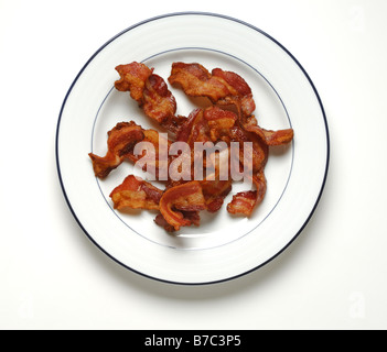 Tranches de bacon cuit sur une assiette blanche ronde Banque D'Images