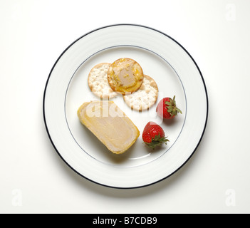 Foie gras, les craquelins et les fraises sur une assiette blanche ronde Banque D'Images