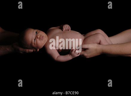 Un bébé de quatre mois garçon tenu par sa maman et papa noir blanc Banque D'Images