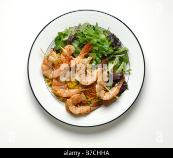 Crevettes grillées sur des brochettes en bois jaune sur le riz et une salade verte servie sur une assiette blanche ronde Banque D'Images