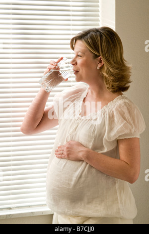 À la femme enceinte de boire un verre d'eau Banque D'Images