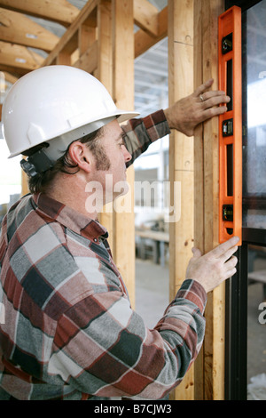 Un travailleur de la construction contrôle qu'une fenêtre nouvellement installé est de niveau vue verticale contenu authentique et précise Banque D'Images