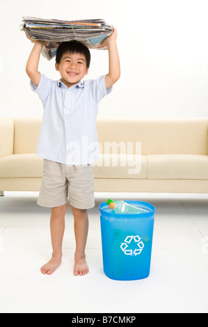 Little Boy holding pile de journal sur la tête et sourire heureux Banque D'Images