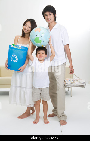 Jeune famille avec un enfant holding newspaper globe and bottle bank Banque D'Images