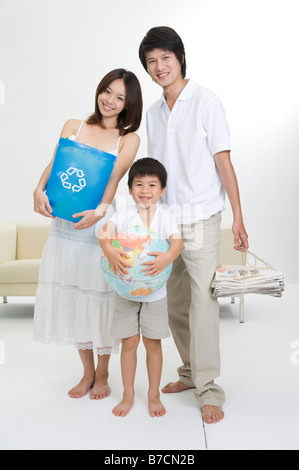 Jeune famille avec un enfant holding globe godet et de journaux Banque D'Images