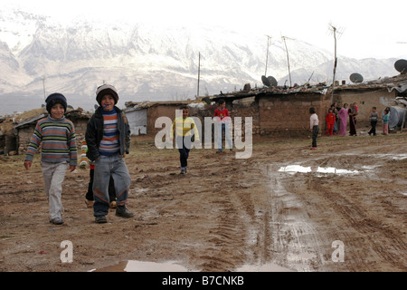 Les enfants curieux en face de huttes de boue dans un petit village près de Amedi kurde dans le nord de l'Iraq en face de montagnes enneigées Banque D'Images