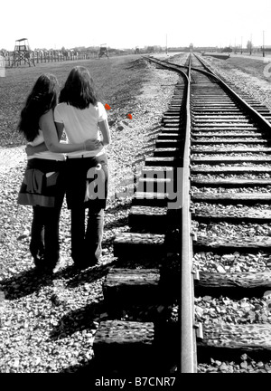 Deux femmes avec des roses rouges debout à côté voies ferrées à Auschwitz, camp de concentration d'Auschwitz, Pologne Banque D'Images