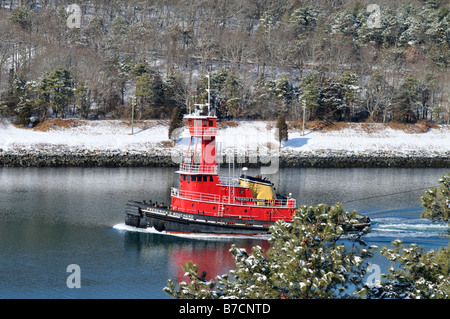 Pittoresque d'hiver avec de l'eau croisière remorqueur rouge la neige et les arbres à feuilles persistantes sur Cape Cod Canal, USA Banque D'Images