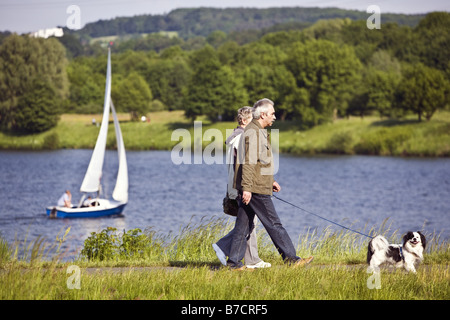 Paire de personnes âgées walking with dog à la frontière de l'Allemagne, Stausee Kemnader, Rhénanie du Nord-Westphalie, Ruhr, Witten Banque D'Images