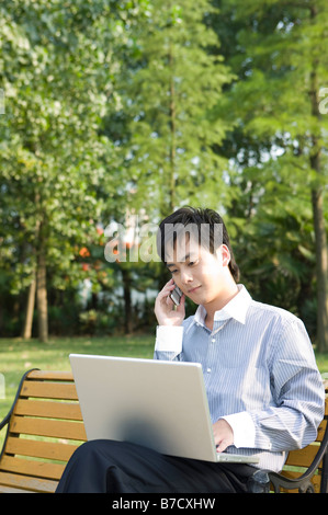 Une entreprise assis sur le banc et à l'aide d'ordinateur portable et téléphone mobile Banque D'Images