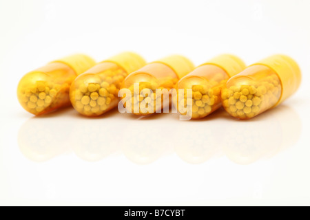 Capsules médicale jaune closeup détail avec réflexion sur fond blanc Banque D'Images