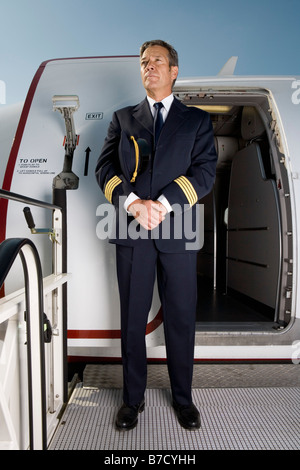 Un pilote debout devant la porte d'un avion Banque D'Images