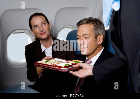 Les gens d'affaires dans un avion d'être servi de la nourriture de la compagnie aérienne Banque D'Images