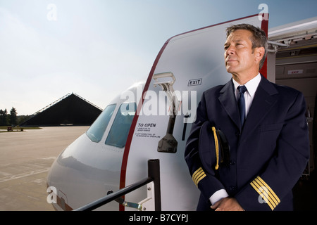 Un pilote debout devant la porte d'un avion Banque D'Images