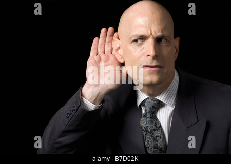 Un homme tenant sa main à son oreille Banque D'Images