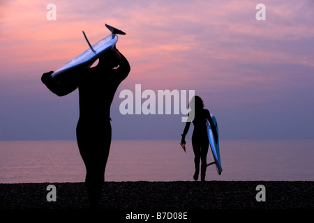 Surfers portent leurs conseils à la plage et prendre le dernier jour de l'hiver au large de Brighton dans l'East Sussex. Photo par Jim Holden Banque D'Images