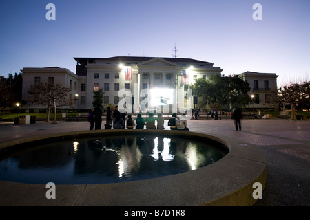 Les étudiants et les résidents s'asseoir sur Sproul fontaine à l'Université de Californie à regarder la couverture de l'inauguration. Banque D'Images