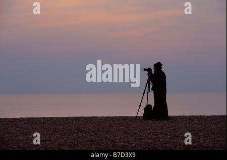 Photographe amateur avec son appareil photo sur la plage de Brighton dans l'espoir de détacher la étourneaux qu'ils s'apprêtent à se percher pour la nuit. Banque D'Images