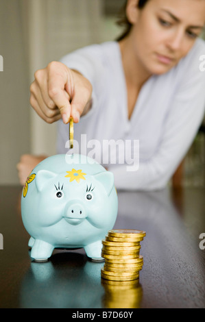 Femme passant d'argent dans une tirelire. Banque D'Images