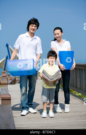 Jeune famille avec un enfant holding newspaper bottle bank et du godet pour recyclage Banque D'Images