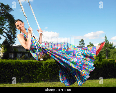 Femme sur une balançoire, ciel bleu au-dessus Banque D'Images