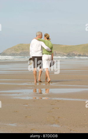 Couple walking arm in arm sur une plage Banque D'Images